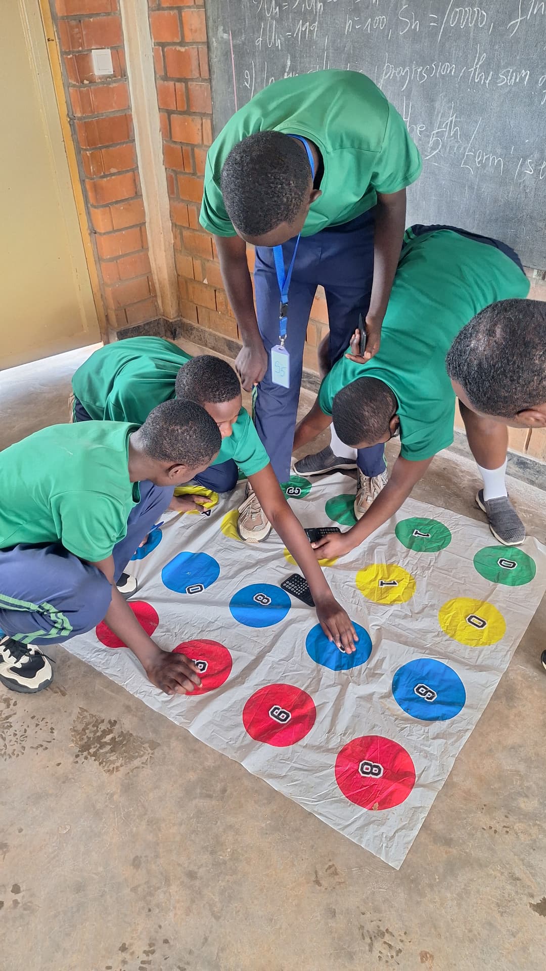 Students playing Twisters on the floor mat in a classroom